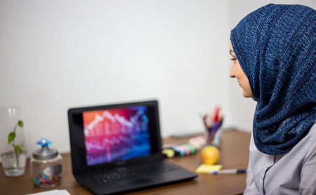 Covered young Muslim with hijab, in office, business and finance, laptop on office desk, economy, accountingの写真素材