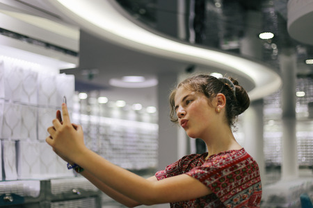 Young blond cute girl posing while taking a photo of herselfの写真素材