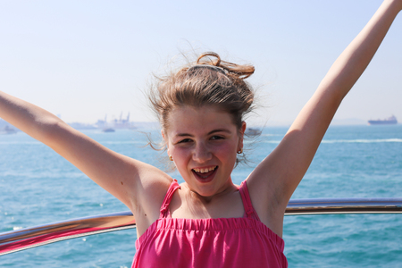Girl enjoys driving on a ferry, sunny day, smile on her face, background blue seaの写真素材