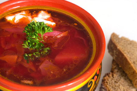 Pot of traditional Russian and Slavic cabbage soup with tomatos, beat, onion and carrot served with sour cream, rye bread and garlicの写真素材