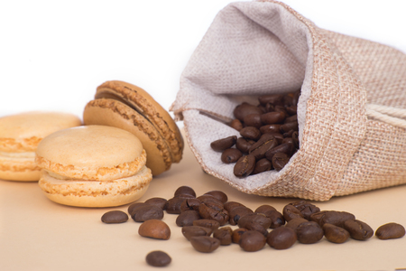 Coffee pouch with coffee grains next to cookies macaroons on pastel color table isolated on white backgroundの写真素材
