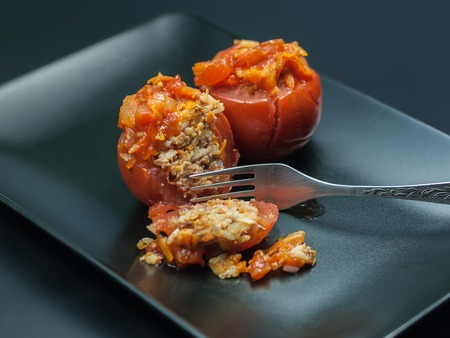 Filled tomatoes appetizer on black plate and dark backgroundの写真素材