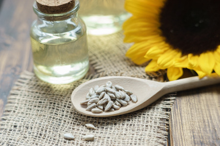 Still life with oil bottles, sunflower and seeds on wooden tableの写真素材