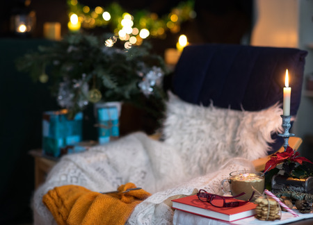 Comfortable place in decrated room for Christmas with chair, plaid, knitting, coffee and sweets. Toning.の写真素材