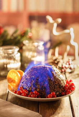 Christmas pudding flambe on wooden table in rusticの写真素材