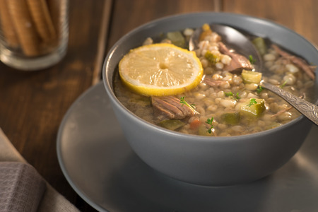 Meat soup with lemon, wine and bread in rustic styleの写真素材