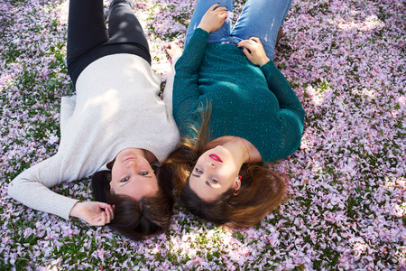 Two young woman on grass with petalsの写真素材