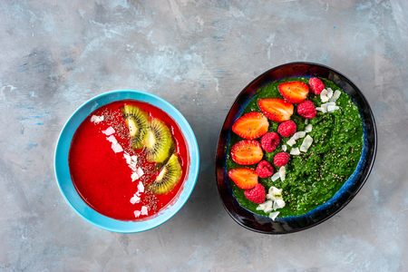 Top view of plates with colorful strawberry and spinach smoothies on bright green background.の写真素材