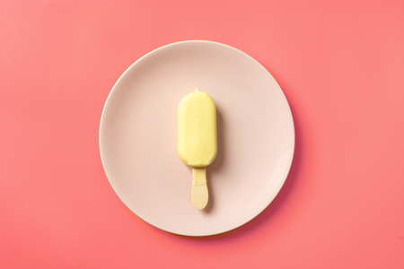 Ice cream popscicle in white chocolate and on pink plateの写真素材