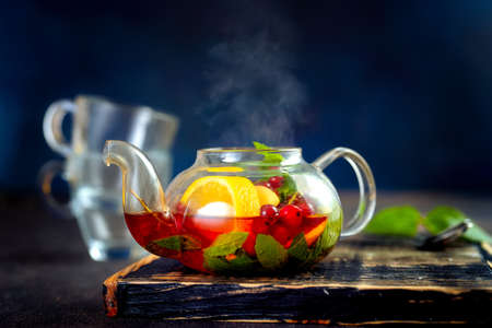 Close up of tea pot with hot fruit tea against dark blue backgroundの写真素材