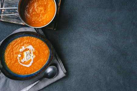 Top view of pumpkin soup in a plate and pot forming left rim on shot. Copy spaceの写真素材