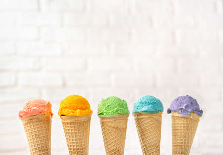Colorful rainbow ice cream cones on yellow backgound. Summer concept