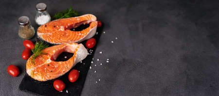 Top view of two raw fresh salmon rich in omega-3 oil on a dark background. Healthy and dietary food. Copy space. Flat layの写真素材