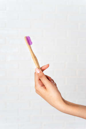 Close up of woman's hand holding bamboo eco toothbrush on white backgroundの写真素材