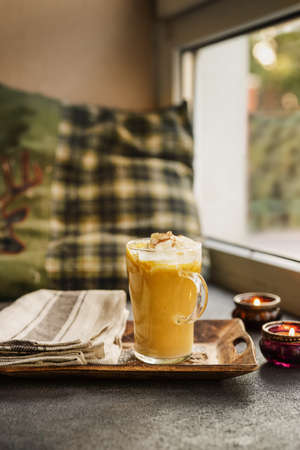 An autumn composition of pumpkin latte in a glass cup on the windowsillの写真素材