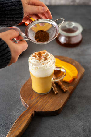 A glass cup of spicy pumpkin cappuccino on grey backgroundの写真素材