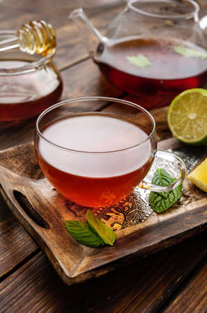 Glass tea cup with mint leaves and lemon on dark wooden tableの写真素材