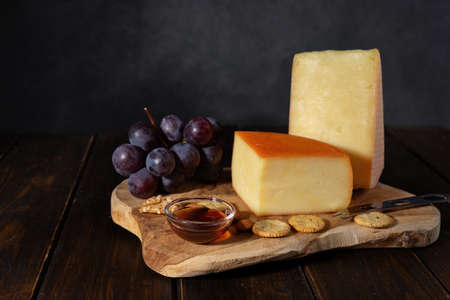 Cheese composition on a wooden tray with nuts and honey in rustic stlyleの写真素材