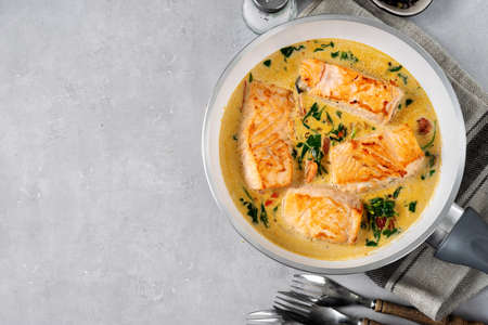 Delicious salmon peaces in cream sauce and frying pan. Copy spaceの写真素材