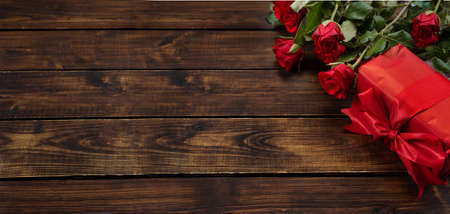 Bouquet of red roses and gift in red paper. Valentines day concept. Long bannerの写真素材