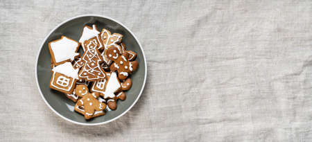 Homemade gingerbread cookies in a plate on light wrinkled fabric background. Christmas holidays concept. Top view. Long banner with copy spaceの写真素材