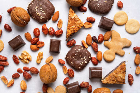 Assortment of chocolate, cookies and sweets for Christmas on light background. Top view