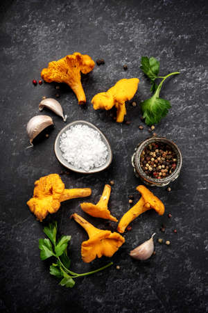 Chanterelles mushrooms and spices on black background. Top view