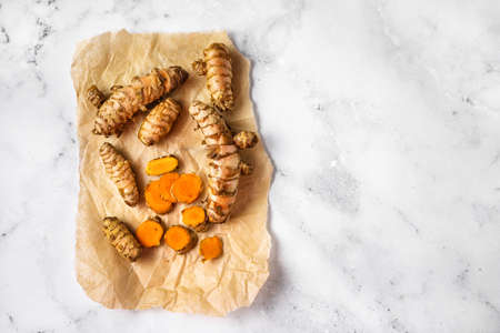 Top view of turmeric curcuma roots on crumpled paper and white background. Immune boosting winter...