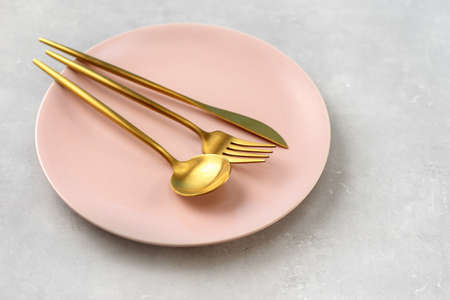 Beautiful pink plate and gold cutlery on grey backgroundの写真素材
