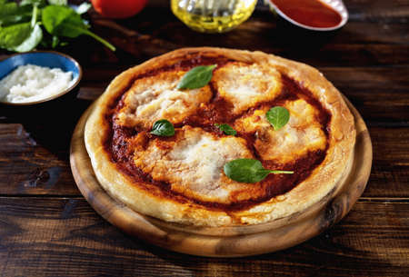Homemade vegan Margherita pizza on rustic wooden background