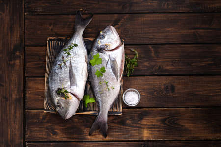 Top view of two dorado fishes on cutting board and rustic background