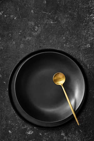 Vertical shot of empty black plate for soup on black bacgroundの写真素材