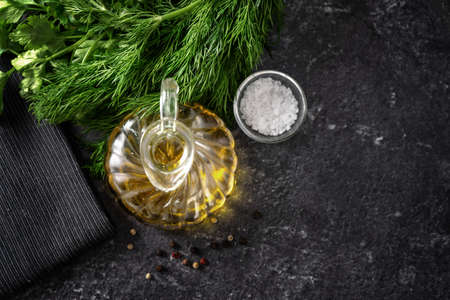 Top view of herbs, olive oil and salt on black background