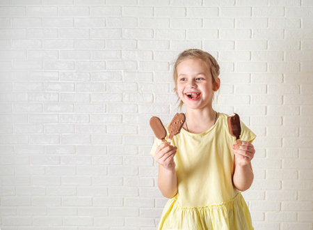 Happy little girl eating ice creams at summer timeの写真素材