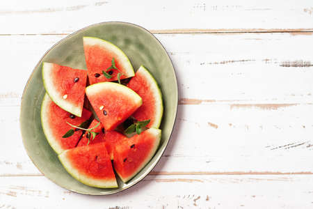 Sliced watermelon in big green plate and white backgroundの写真素材