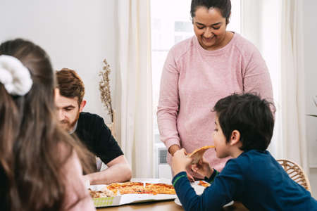 Mixed family eating vegan pizza at lunch at home. Vegan food. Diversity and real people