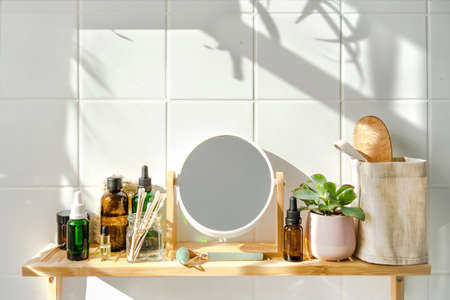 Shelf in bathhroom with zero waste cosmetic items and reusable bottles. Shadows from the window. Wellness and sustainability conceptの写真素材