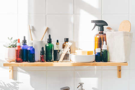 Close up of reusable cosmetic bottles on bamboo shelf against white wall. Zero waste, wellness conceptの写真素材