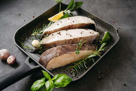 Raw halibut fish steaks with herbs and lemon prepared for cooking in a grill pan. Healthy omega 3 unsaturated fats source good for brain and mental clarityの写真素材