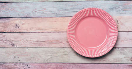 Empty pink plate on pastel wooden background for Easter. Food background for menu, recipe book....