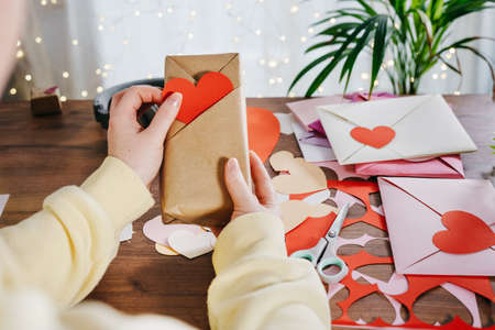 Woman placing a paper DIY heart in a pocket of a gift with Kimono-style wrap. Valentines Day conceptの写真素材