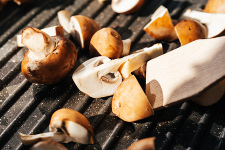 Mushrooms champignons n a grill plate in sun light. Close up. Vegan food concept.