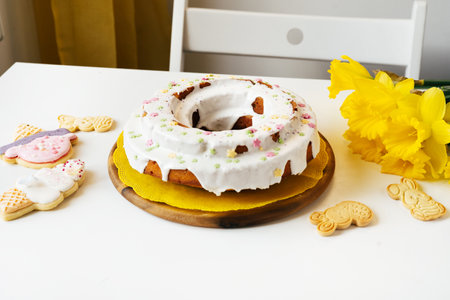 Easter cake, narcissus, cookies on white table background Happy easter backdrop for spring holiday