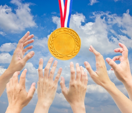 Hands with golden medal in front of blue sky   の写真素材