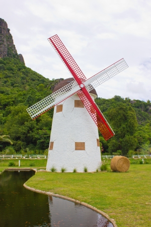 Windmill, hay roll, green field and canal  view in farm の写真素材