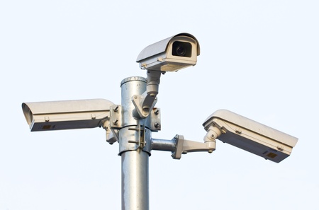 Three security cameras against the blue sky の写真素材