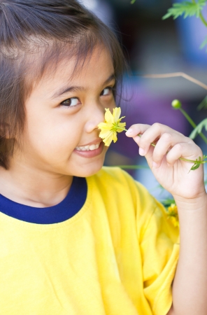 Little girl smelling A Yellow Cosmos Flower.の写真素材