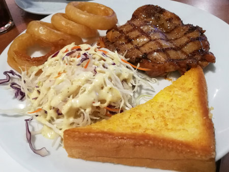 Chicken Steak Vegetable Salad Fried Onion Garlic Bread on White Plate.の写真素材