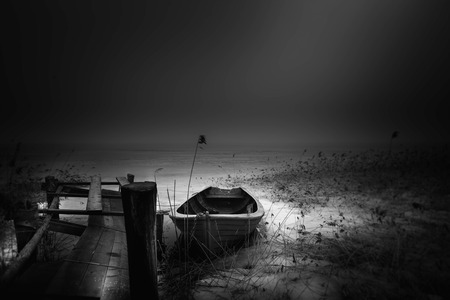 One single out old boat by the old and crooked wodden pier in the cold winter in Swedenの写真素材