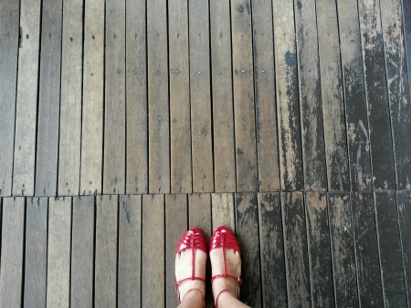 Red sandaled feet on wooden deckの素材